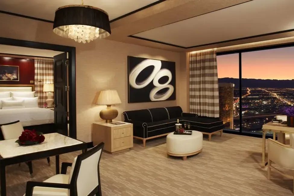Classy furniture fills an expansive suite while floor-to-ceiling windows reveal city and mountain views