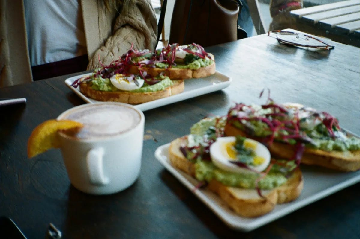 A food view of two plates with open faced egg sandwiches and a cup of coffee at Plate 38.