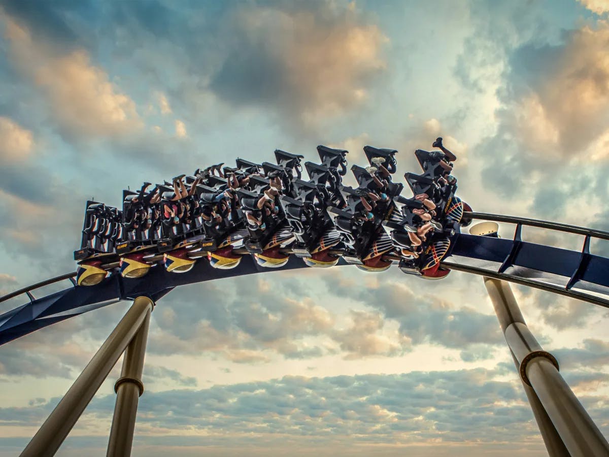 Riders crest the peak of a roller coaster, suspended in a moment of exhilarating anticipation.