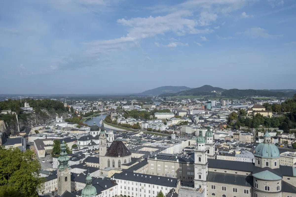 Aerial view of city with buildings, canal and mountains. 