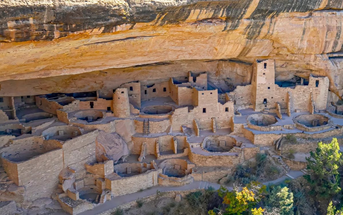 Ruins of many small buildings carved in the side of a canyon. 