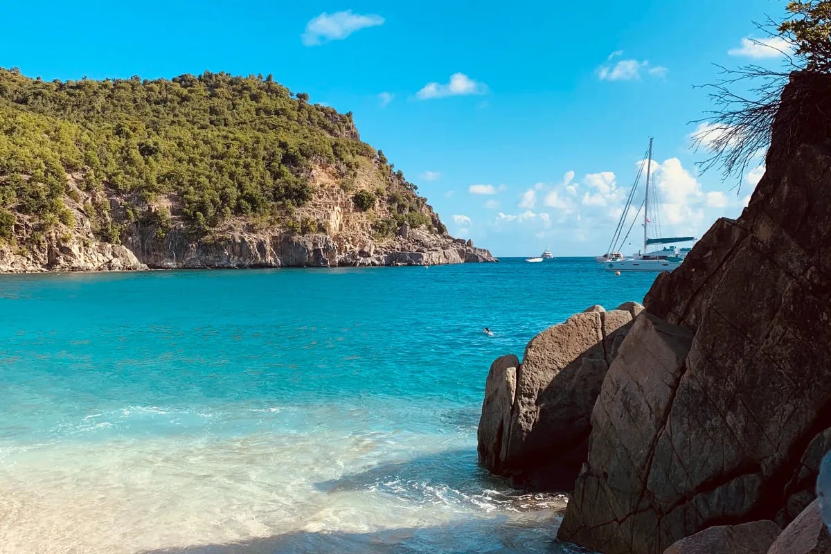 Beach with bright blue water and hills of the island of St Barth's