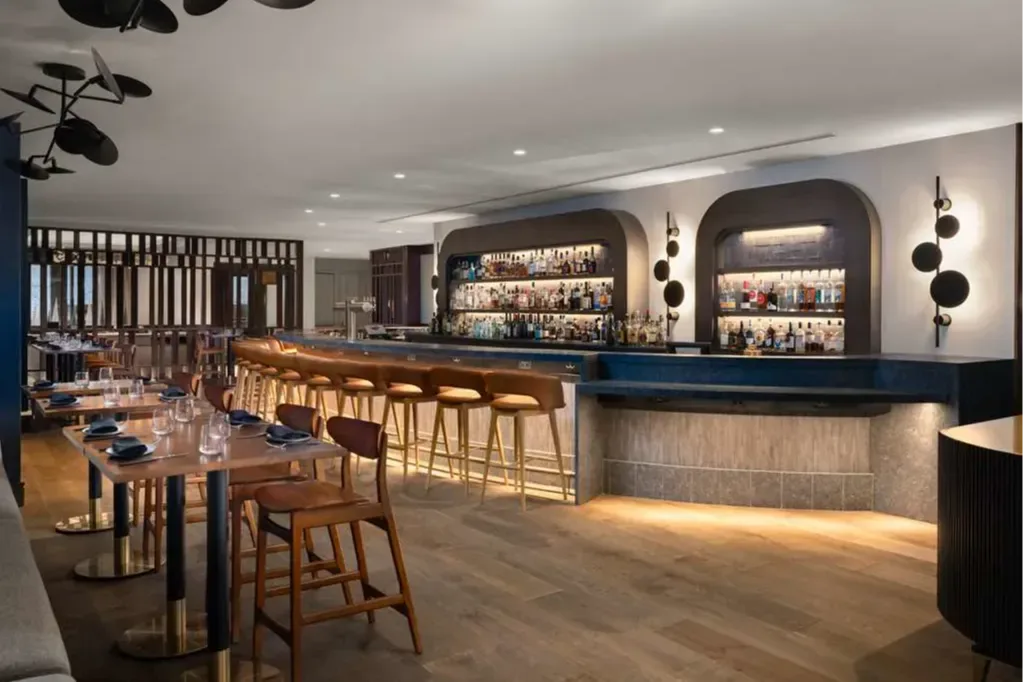 a sleek restaurant dining room with a long bar and wooden floors