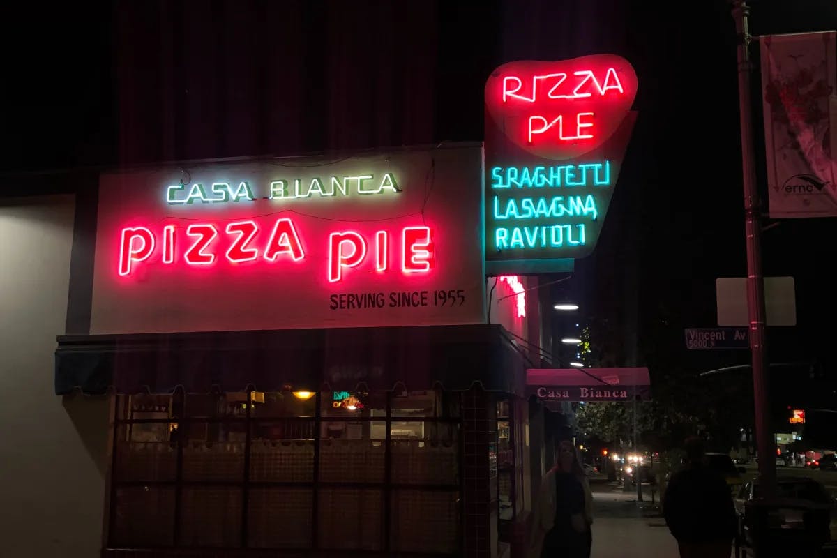 A picture of a pizza restaurant with neon signage.