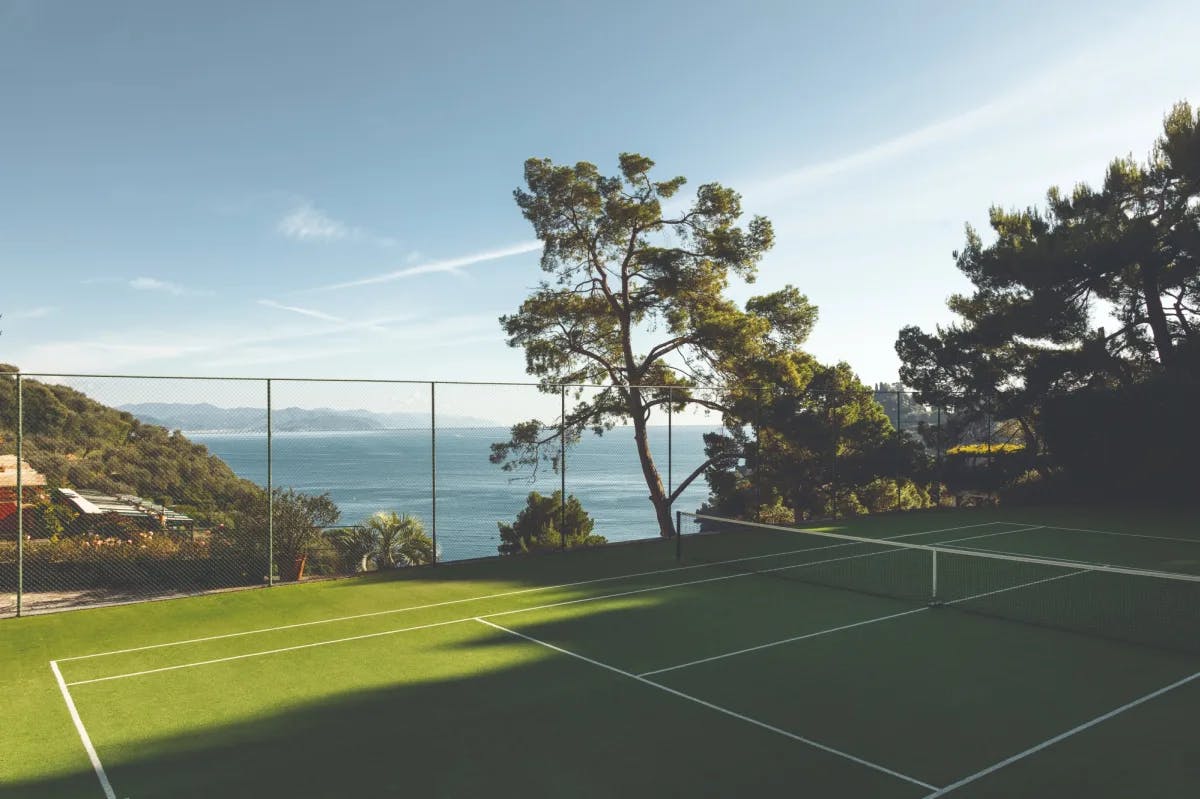 a sleek green tennis court overlooking a bay below