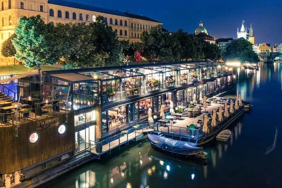The floating restaurant of Marina Ristorante with a view of the Prague Castle in the background at night.