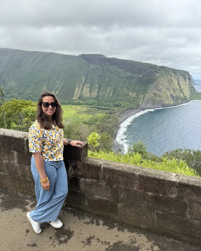 Sharon posing at a lookout point overlooking a beautiful coastal area with steep cliffs on a cloudy day