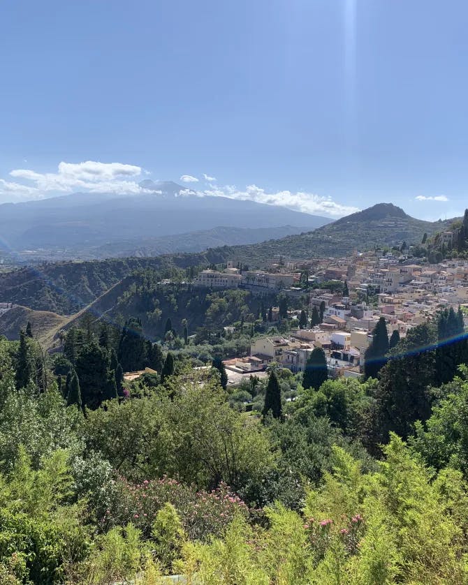 Beautiful view of a coastal city surrounded y nature with mountains in the distance