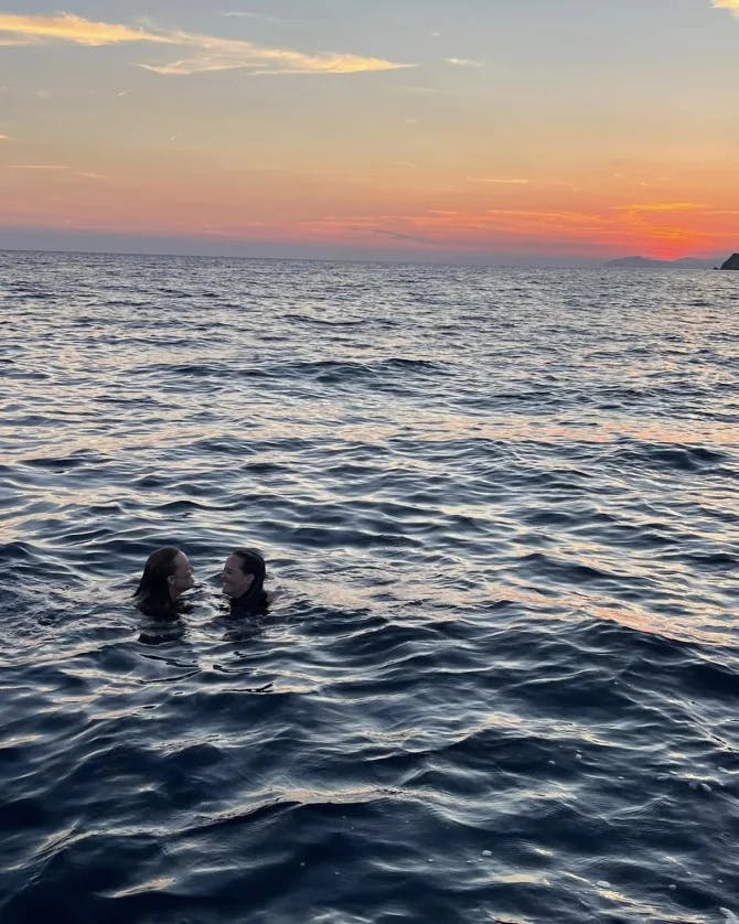 Women swimming in the sea under sunset