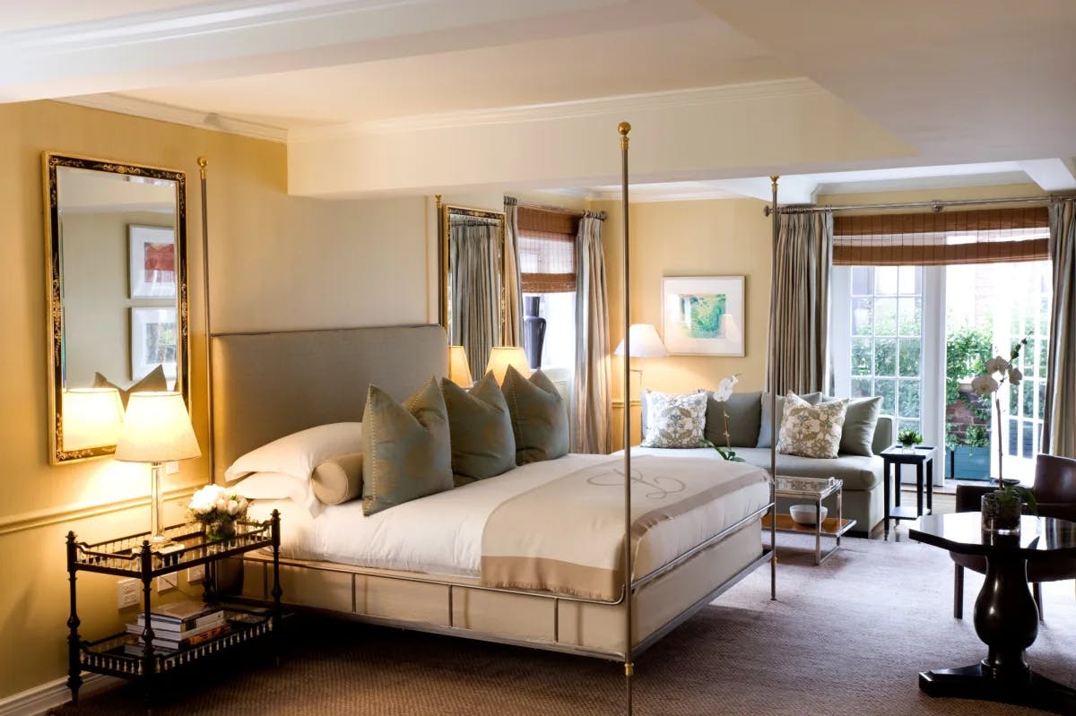 upscale bedroom with a four-poster iron bed and a glass door leading to a terrace