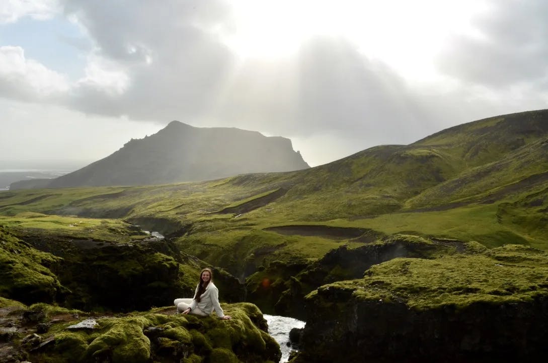 A woman sitting on a green hill. 