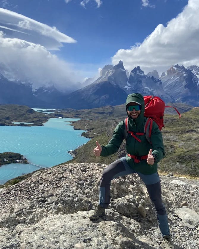 Travel advisor holding a red backpack standing beside lake