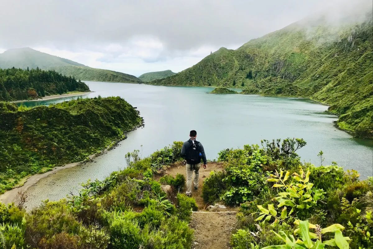 A man hiking out to a peninsula overlooking a river running between two mountain ridges