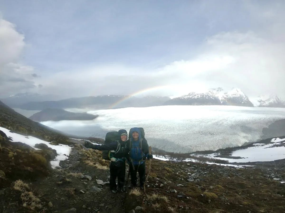 Advisor and friend hiking with a rainbow in the distance.