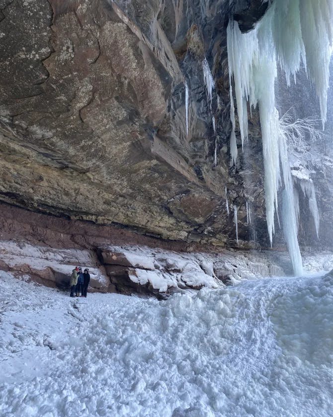 two people standing beneath a frozen waterfall