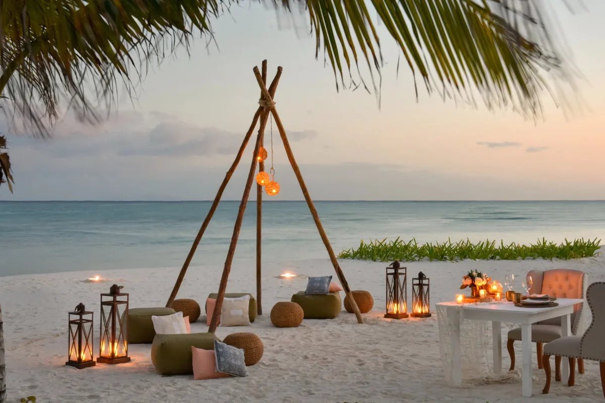 sunset beach with lanterns and a table set for dinner