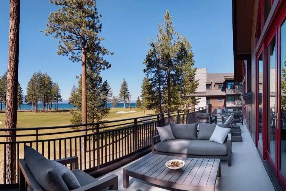 outdoor terrace overlooking lawn and pine trees with lake in the distance