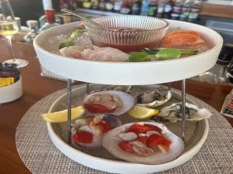 A two-tiered seafood platter with various shellfish is elegantly presented on a bar counter.