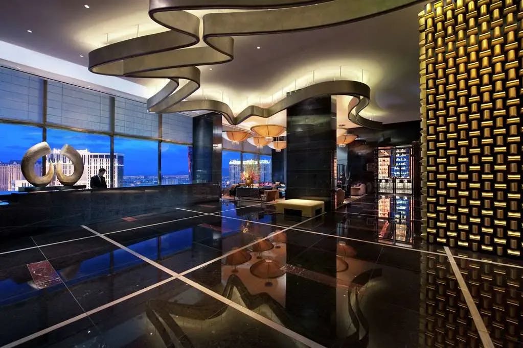 Snazzy, contemporary lobby belonging to Waldorf Astoria Las Vegas with black marble floors and golden lighting