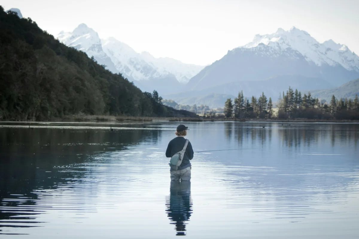 wide river with distant mountain and a single person fly fishing