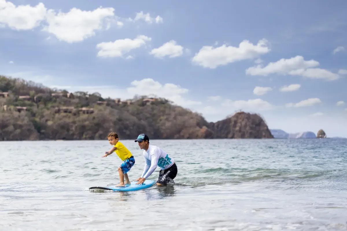 An istructor teaching kid to surf at Four Seasons Resort Costa Rica