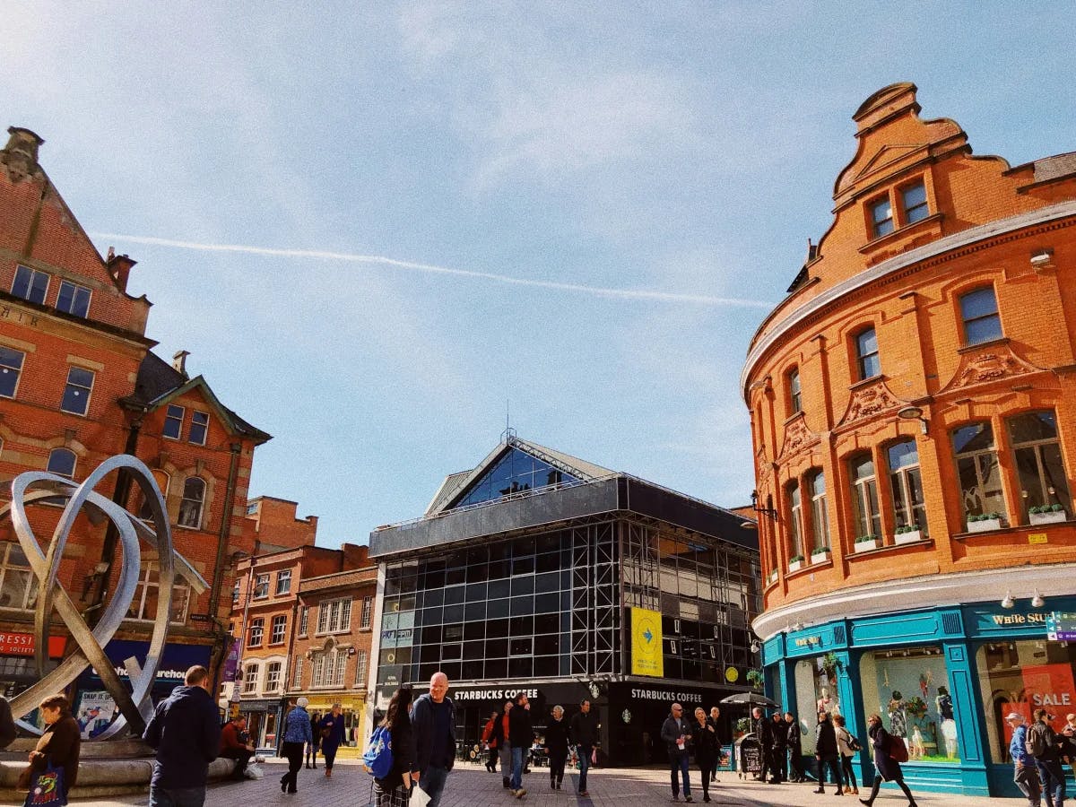 The image captures an urban street scene with buildings, pedestrians, and a clear blue sky.