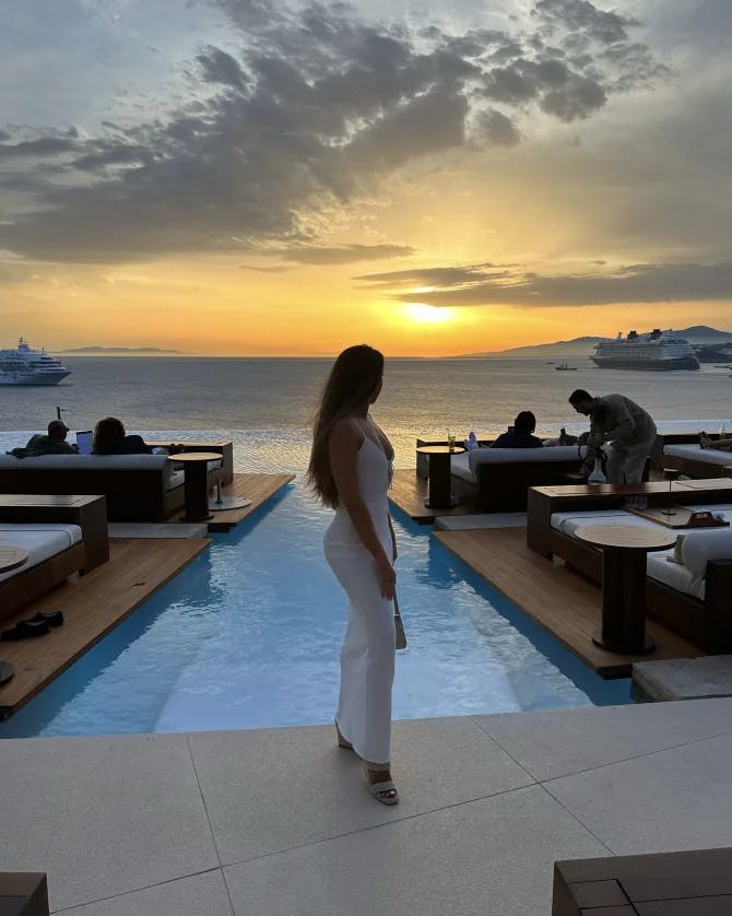 Advisor posing in front of an infinity pool with an ocean view at sunset. 