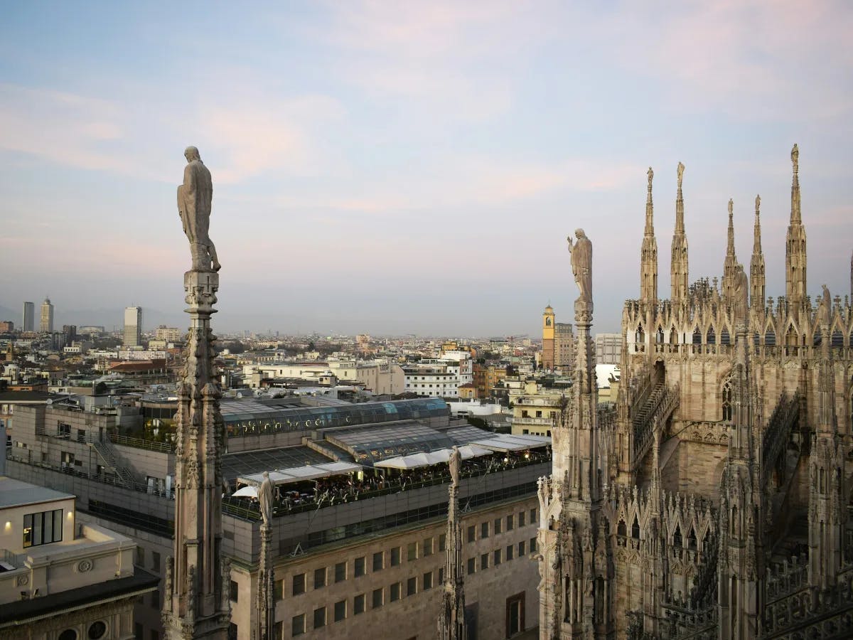 A view of the city from the top of a building with a white concrete statue in the middle during daytime.