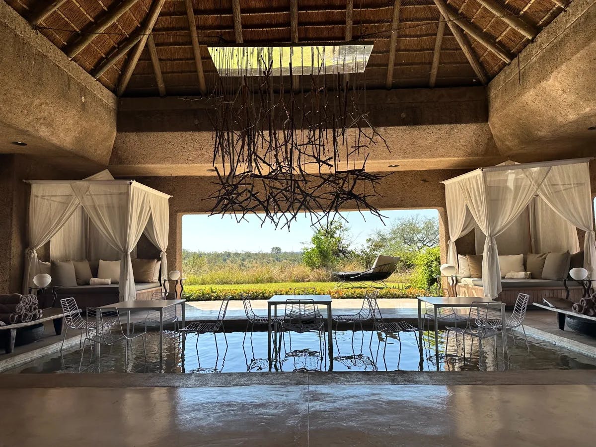 An elegant indoor oasis with a reflective pool and comfortable seating, blending seamlessly with the outdoor view through an open wall.