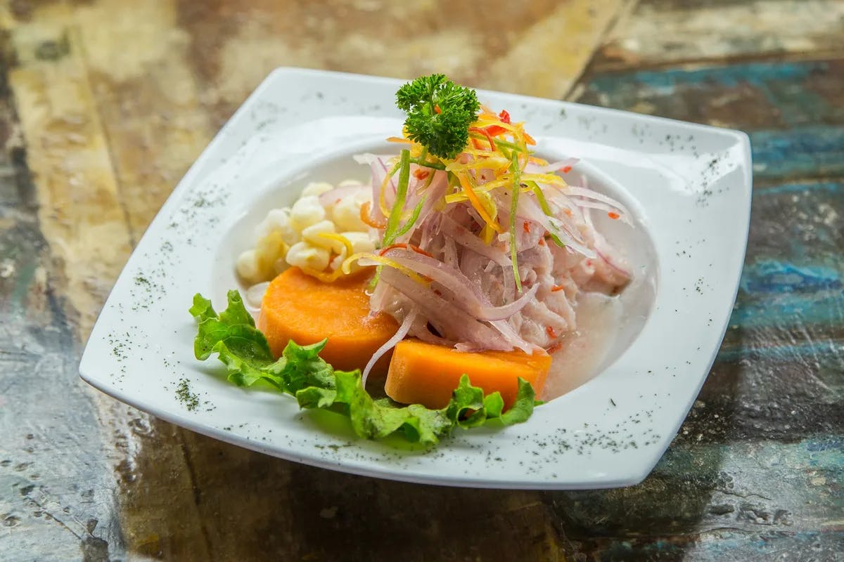 A white plate with salad on a wooden table.