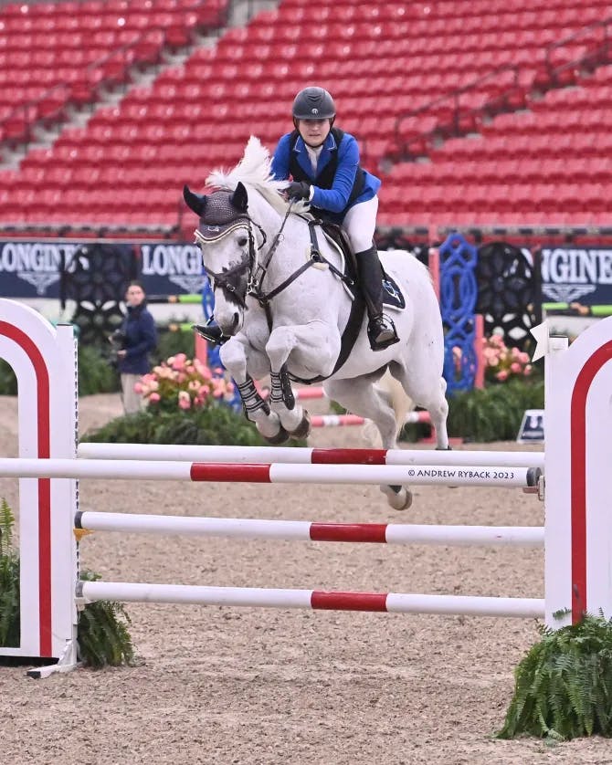 A women riding a horse in a competition and jumping over obstacles