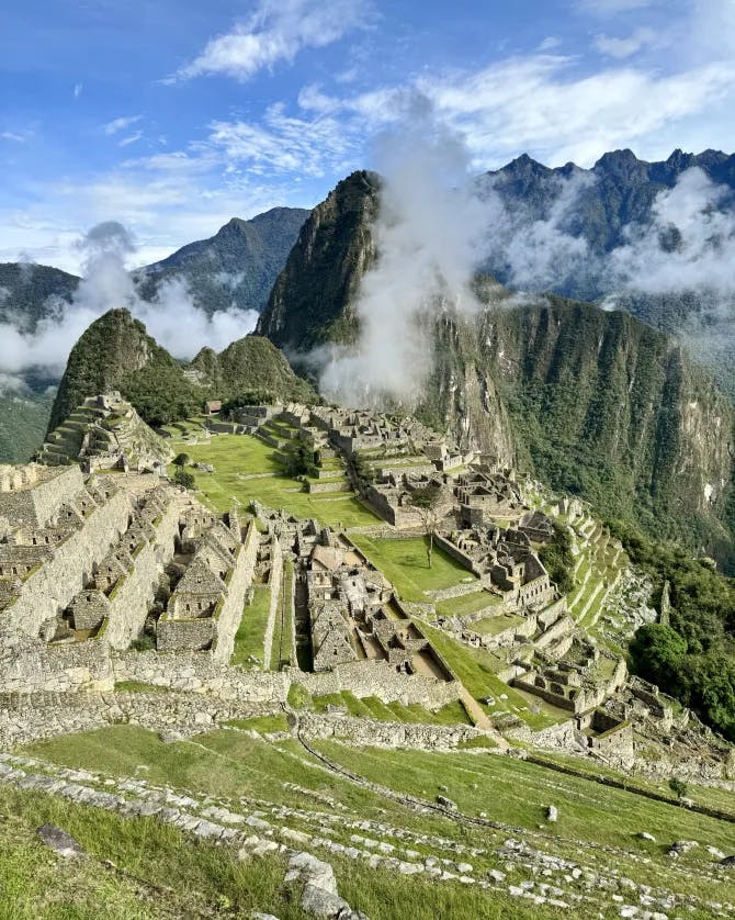 Picture of Historic Sanctuary of Machu Picchu with clouds against the peak in front of a blue sky