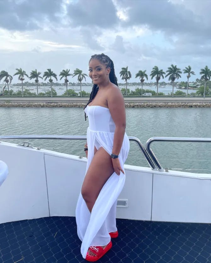 Travel advisor posing on a boat in a long white dress.