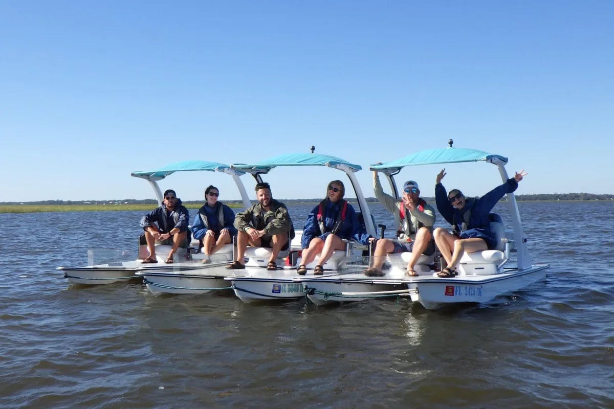 Group of people sitting on small white boats with canopies on a tour through Go-Cat Boats.