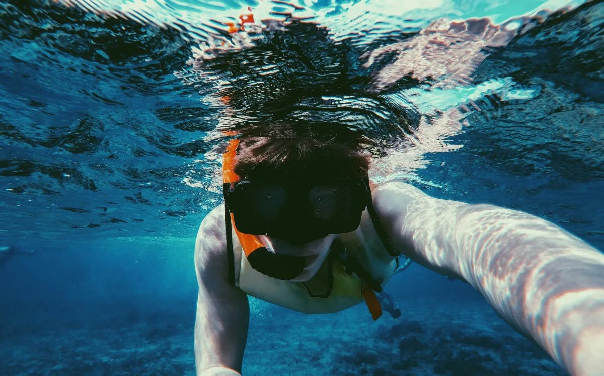 An underwater selfie of a person snorkeling in clear blue waters.