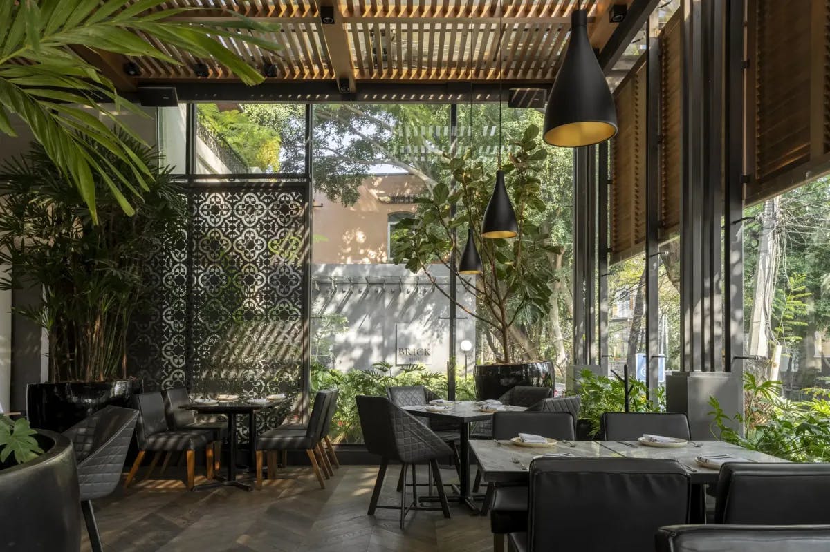 a stylish dining room with floor-to-ceiling windows framing a leafy garden