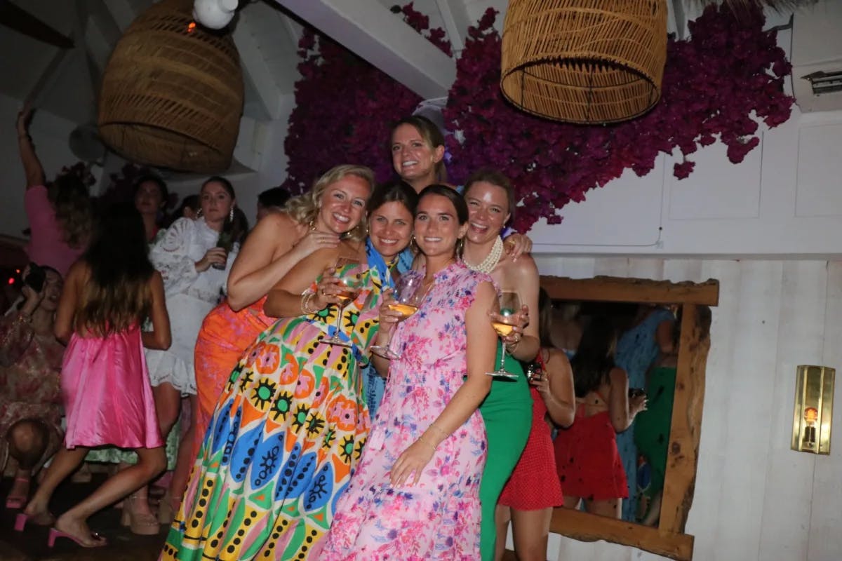 A group of women in colorful dresses holding cocktails at a party.