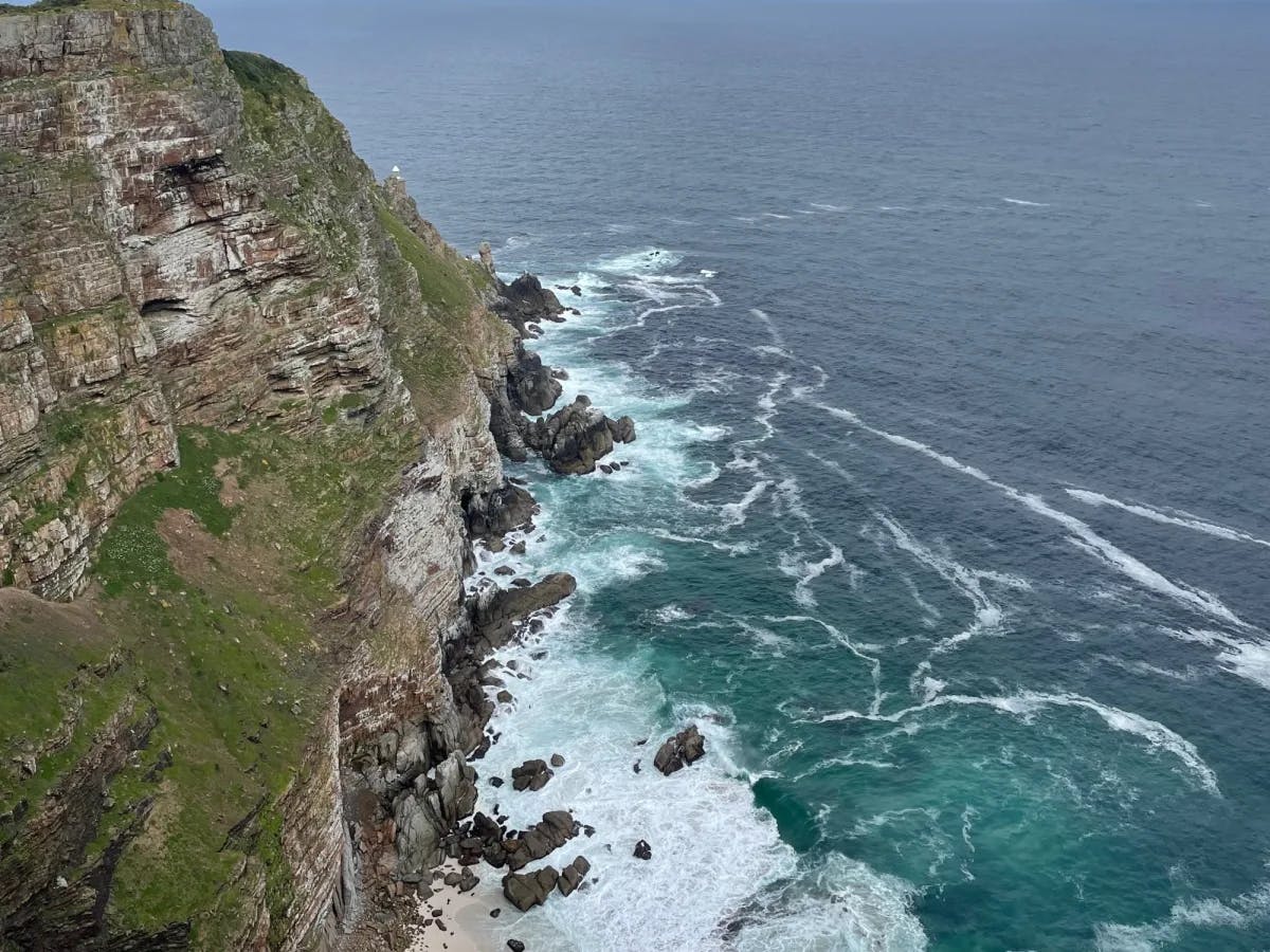 Aerial view of sea shore with cliff at edge.