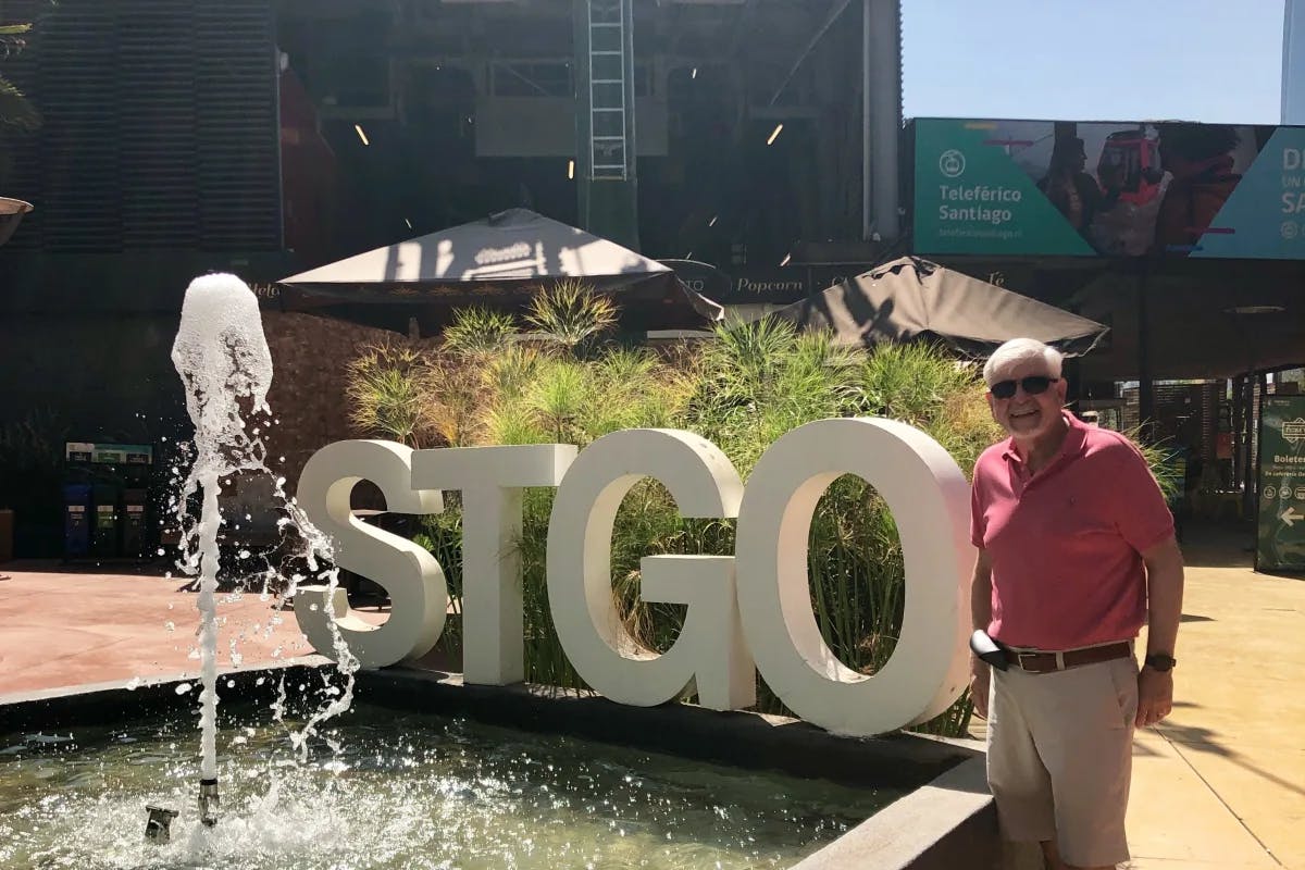 Man standing in front of STGO signage and a small fountain in Santiago, Chile.