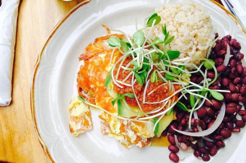 An aerial view of a white plate of mixed healthy foods The Beet Box Cafe in Oahu.