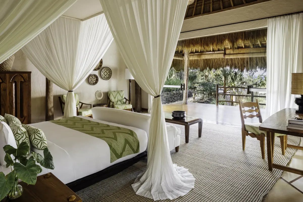 a luxe canopy bed overlooking a terrace in the jungle