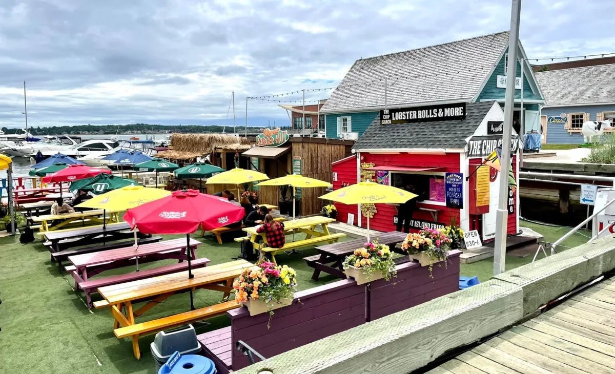 An outdoor dining area with benches and colorful umbrellas by some food trucks