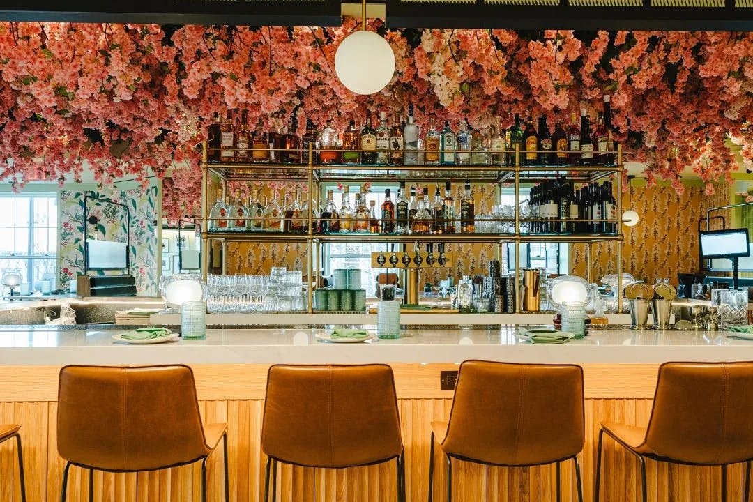 A beautiful bar with a decorative bar and floral arrangements hanging from above. 