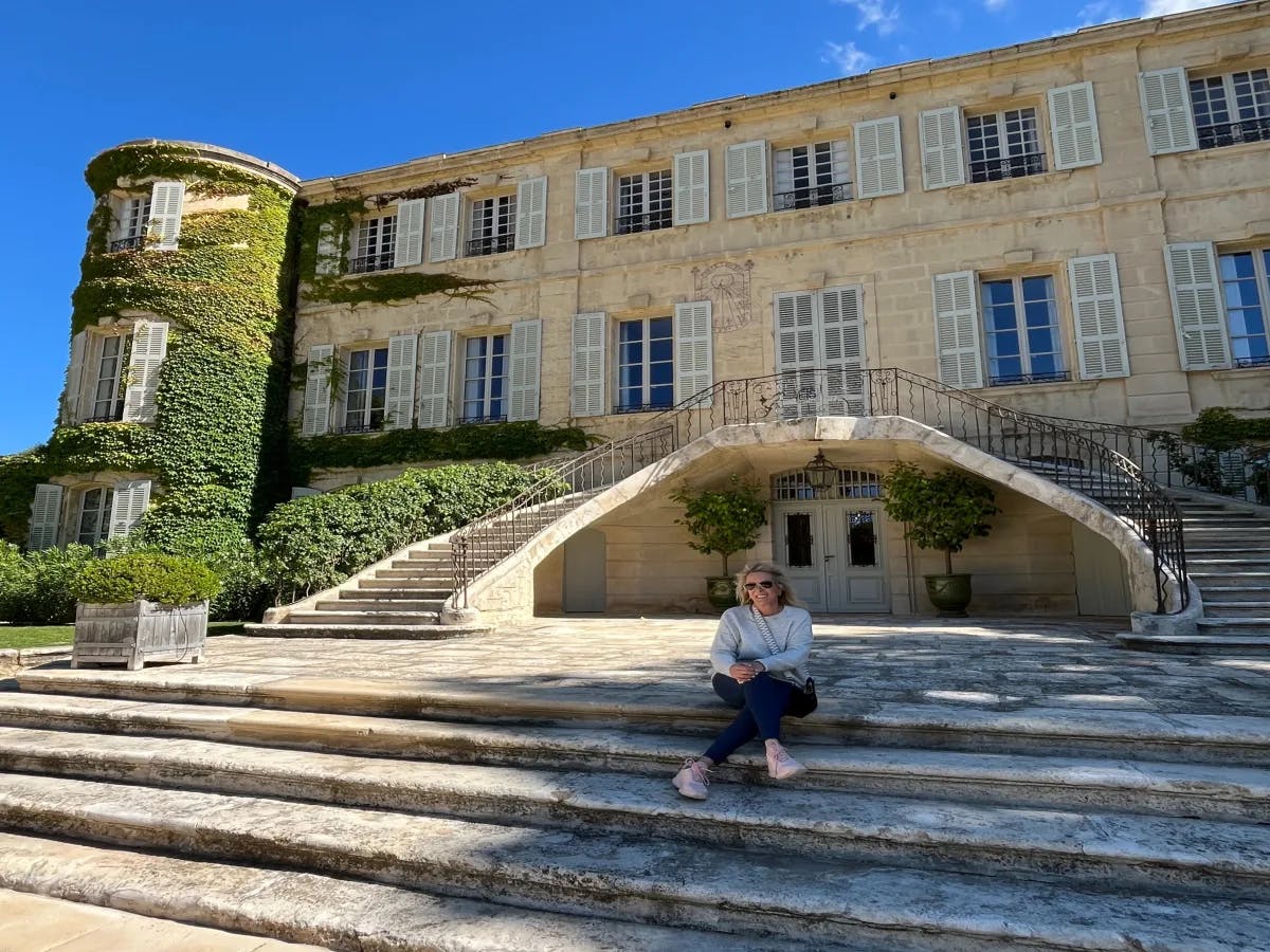 A person relaxing on the steps of a building adorned with ivy, bathed in the warmth of a clear blue sky.