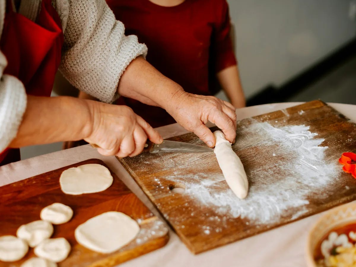 Two hands skillfully working with dough, at a baking session in progress.