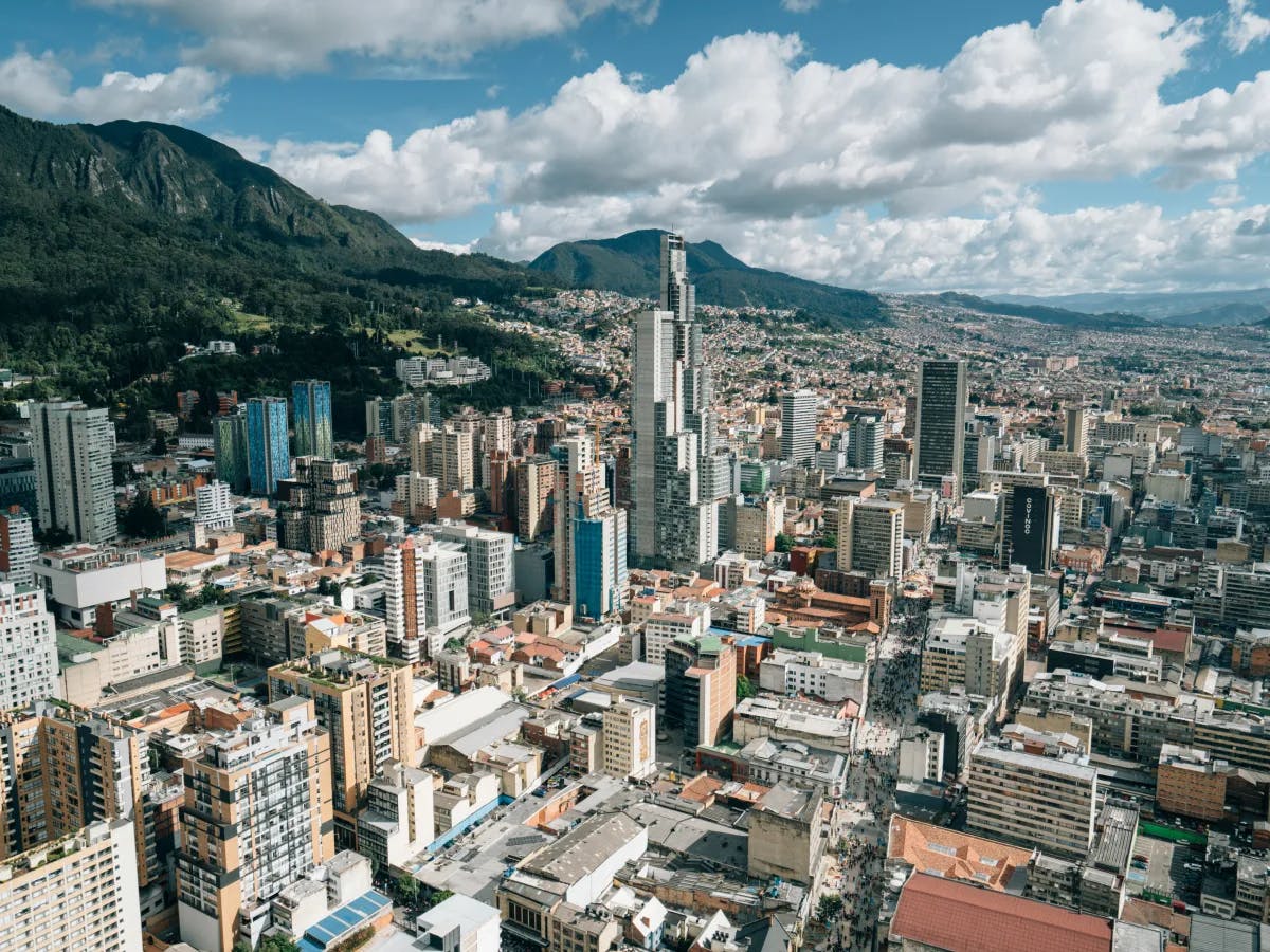 A high-angle view of a bustling cityscape, nestled among mountains under a partly cloudy sky.