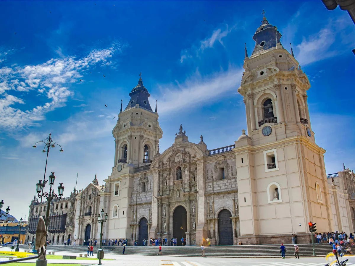 A majestic cathedral with twin bell towers stands as a testament to historical grandeur against the backdrop of a clear blue sky.