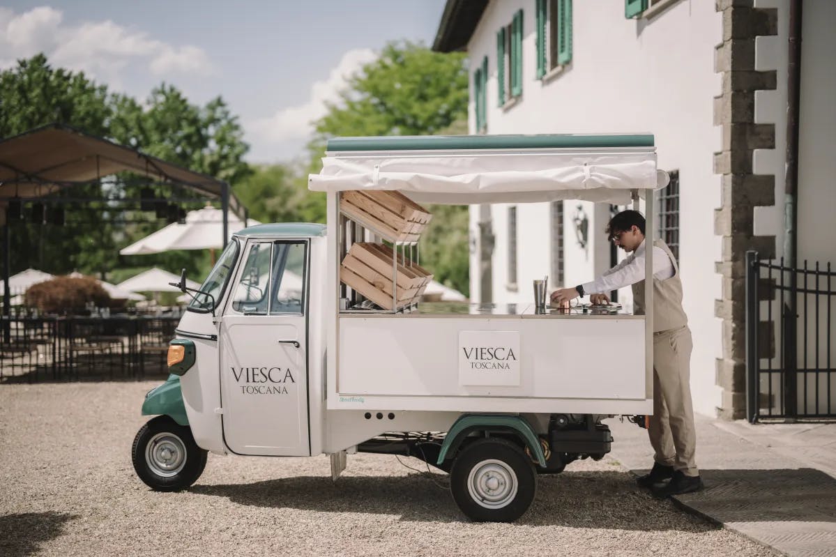 A vintage ice-cream cart with the hotel's name and a man preparing the food.