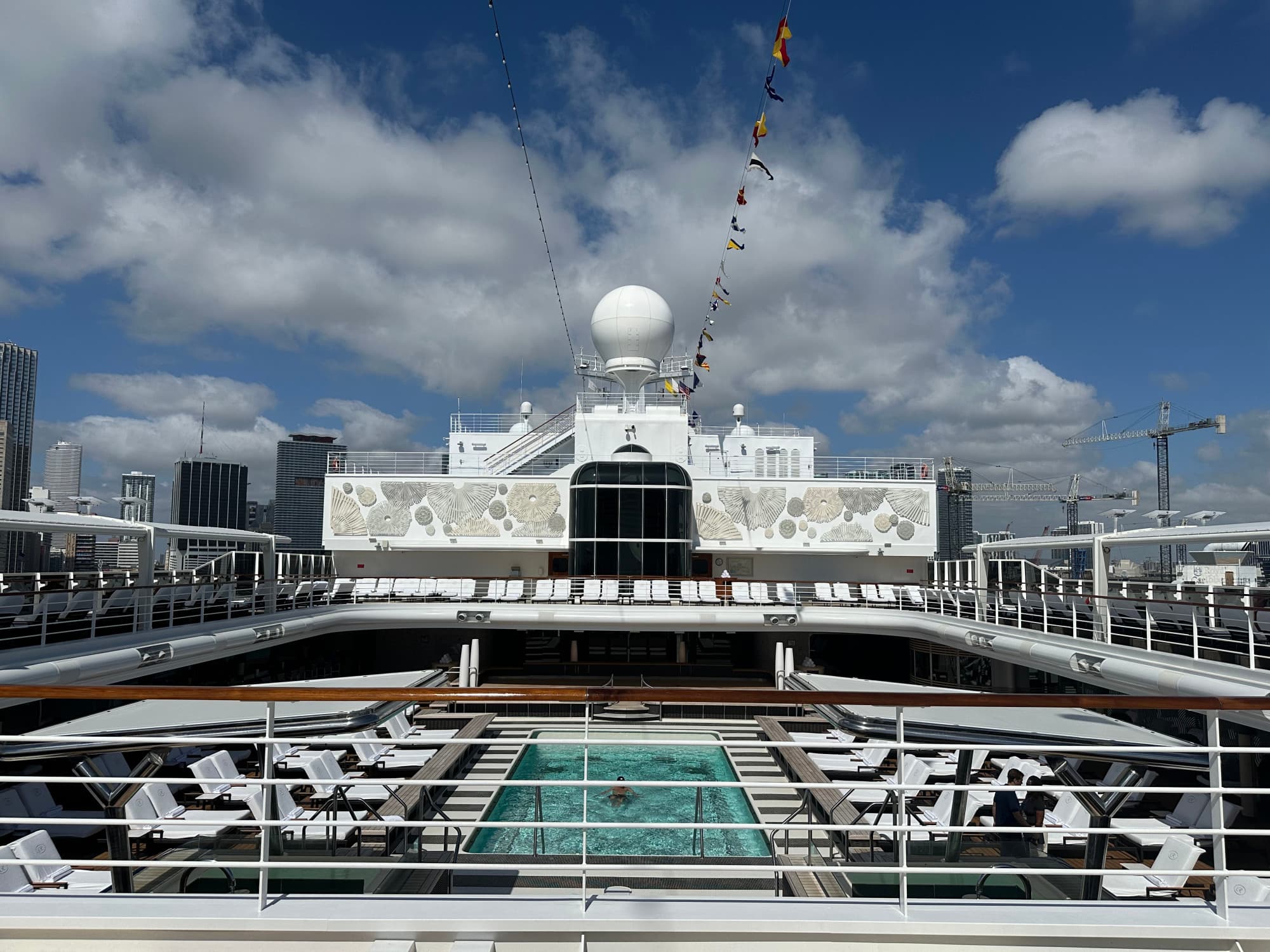 Crusie ship deck with a pool and loungers on a sunny day