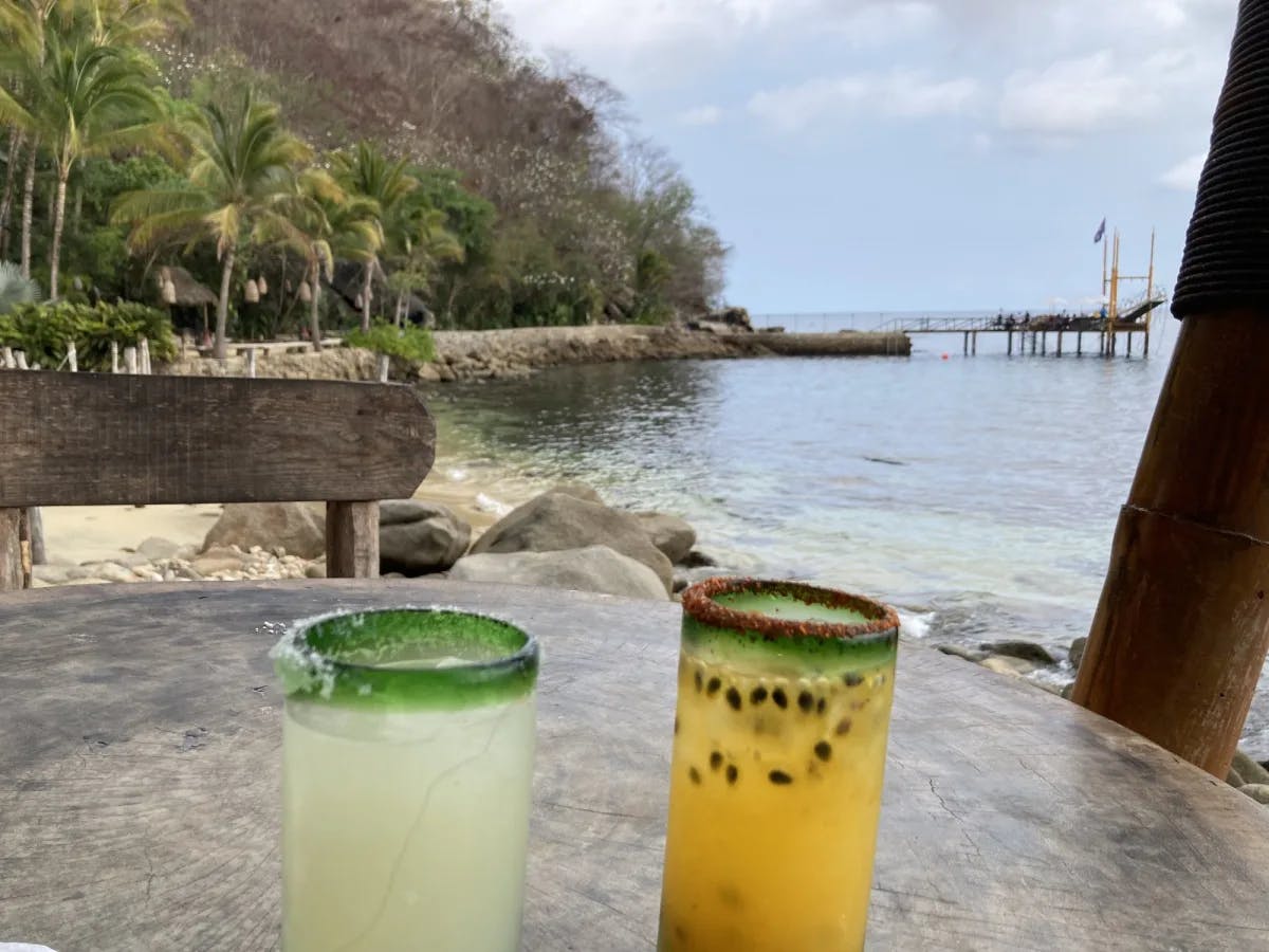 Two drinks on a table near the beach.